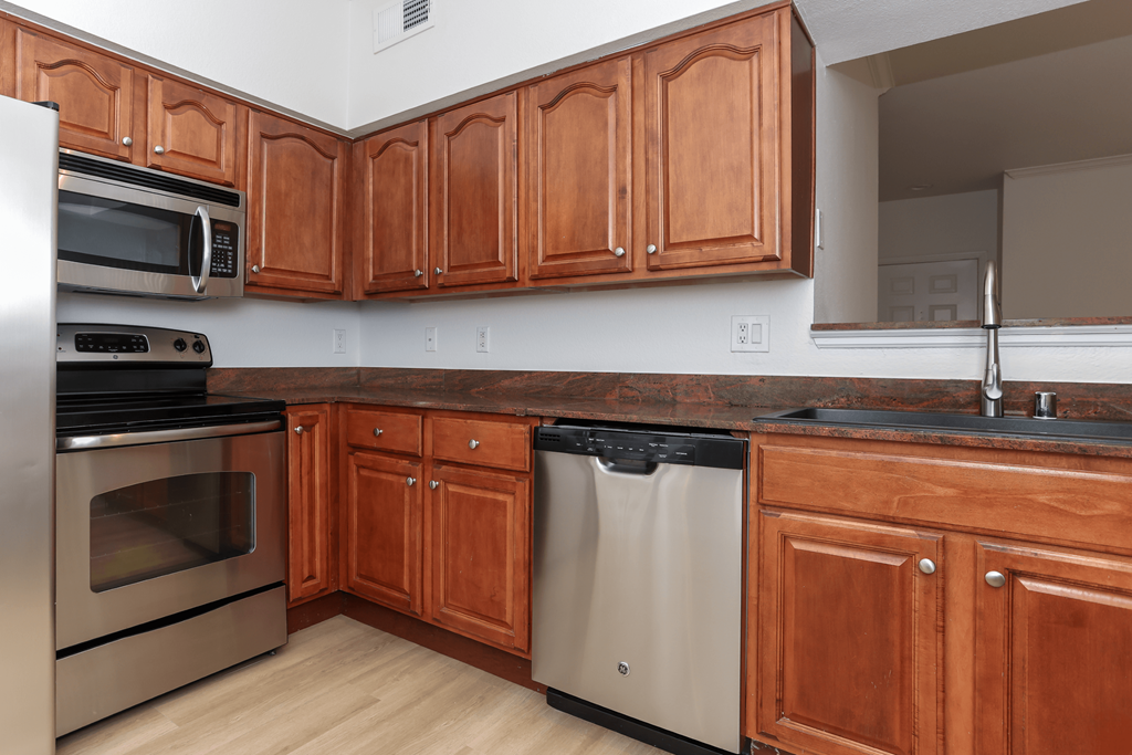 A kitchen with wooden cabinets and a black dishwasher.